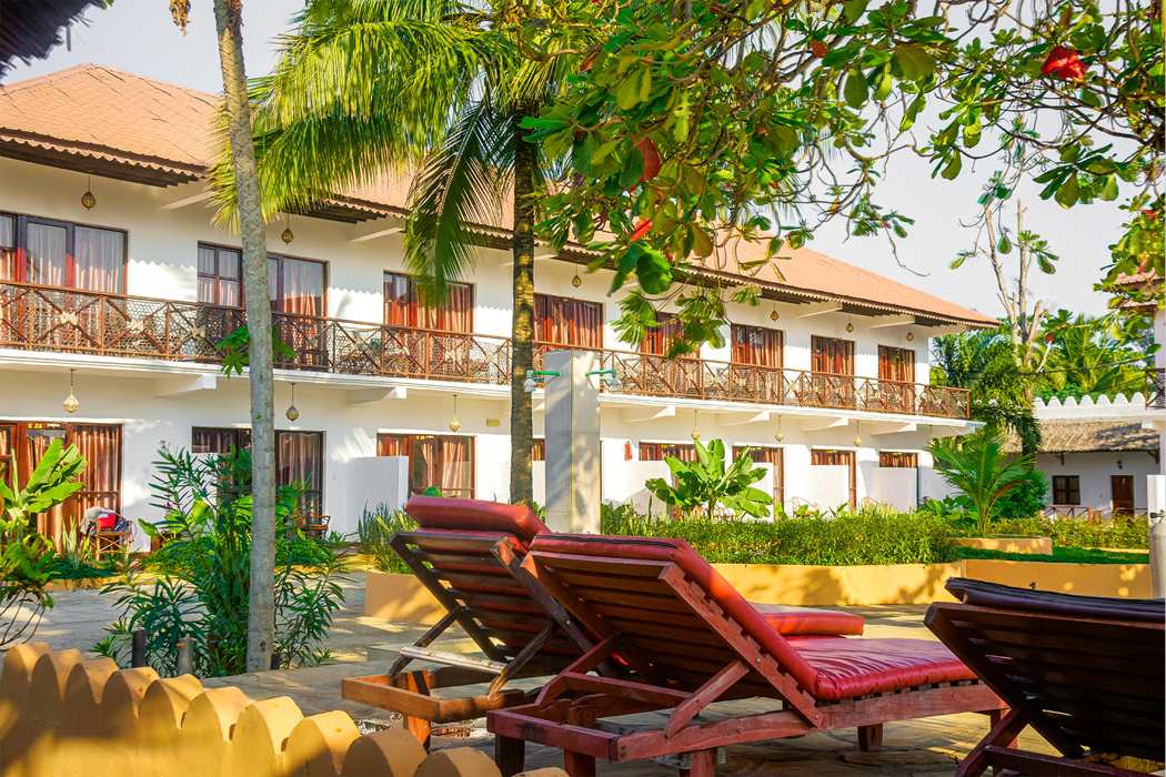 The Amaan Beach Bungalows buildings, palms and sun loungers